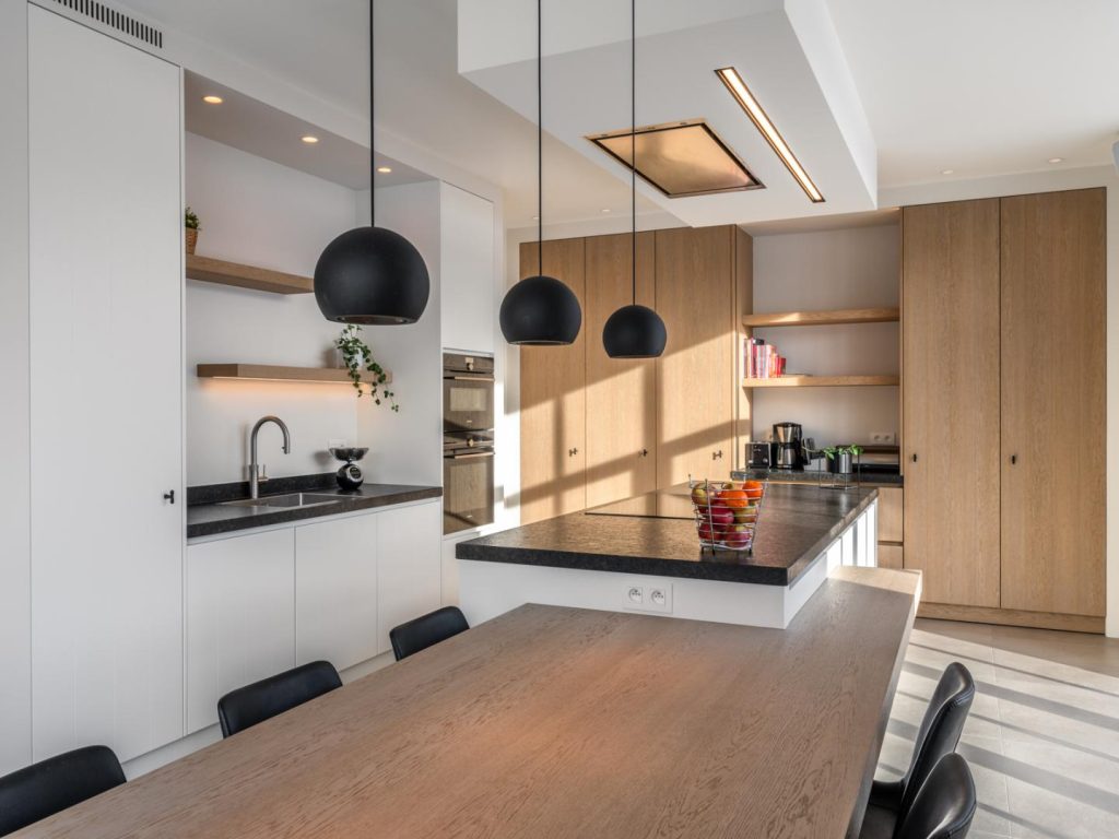 Leefkeuken met een grote eettafel die uitnodigt tot dagelijkse gezinsmomenten en een vlotte connectie met de tuin